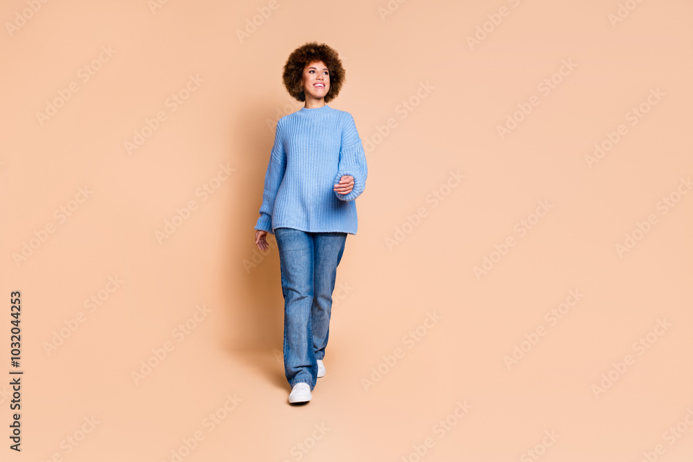 Full size photo of good mood nice girl dressed knit sweater jeans walk look at offer empty space isolated on pastel color background Full size photo of good mood nice girl dressed knit sweater jeans walk look at offer empty space isolated on pastel color background