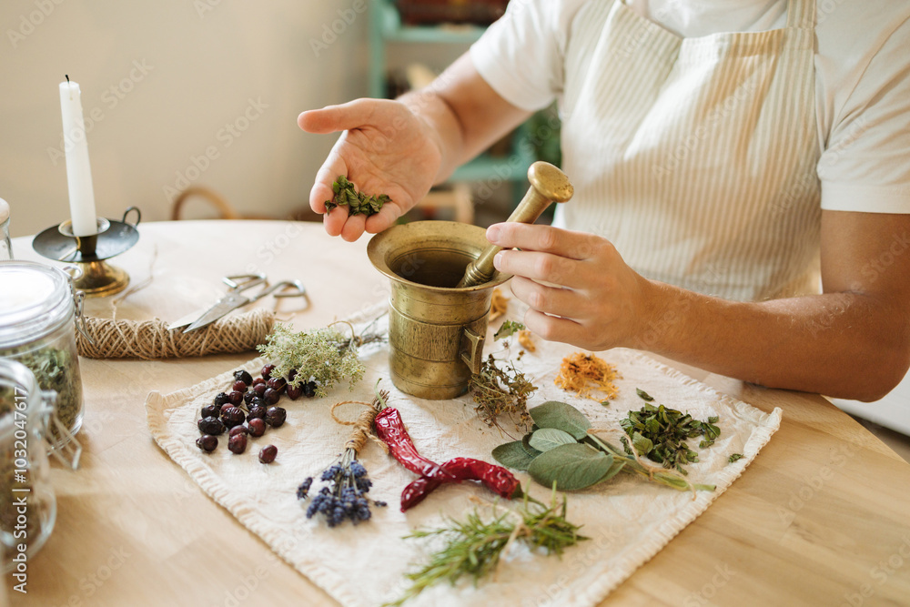 Side view of man adds dried mint to a mortar and pestle. Homemade healthy and nutrition supplements Side view of man adds dried mint to a mortar and pestle. Homemade healthy and nutrition supplements