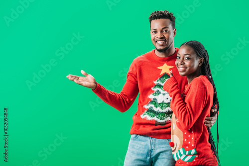 A cheerful couple in festive winter sweaters smiles and embraces, capturing the holiday spirit joyfully.