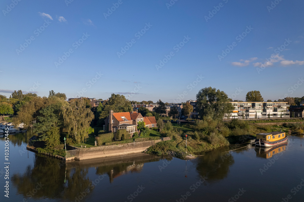 Mayors resident in Zutphen countenance seen from above against a clear blue vibrant colourful sky with quay visible of river IJssel in low water level, historic tower town reflecting in the waterway Mayors resident in Zutphen countenance seen from above against a clear blue vibrant colourful sky with quay visible of river IJssel in low water level, historic tower town reflecting in the waterway