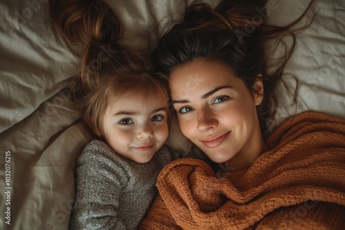 Weekend in bed. Funny latin woman and her child girl lying under blanket, looking at each other and smiling, having fun together at home, top view, Generative AI