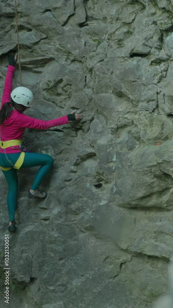 Attractive slim young sportswoman climbing mountain cliff rock using safety ropes and wearing helmet. Alpinist. Hiking. Adventures. Extreme. Attractive slim young sportswoman climbing mountain cliff rock using safety ropes and wearing helmet. Alpinist. Hiking. Adventures. Extreme.
