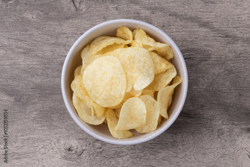 Potato chips in a bowl over wooden table