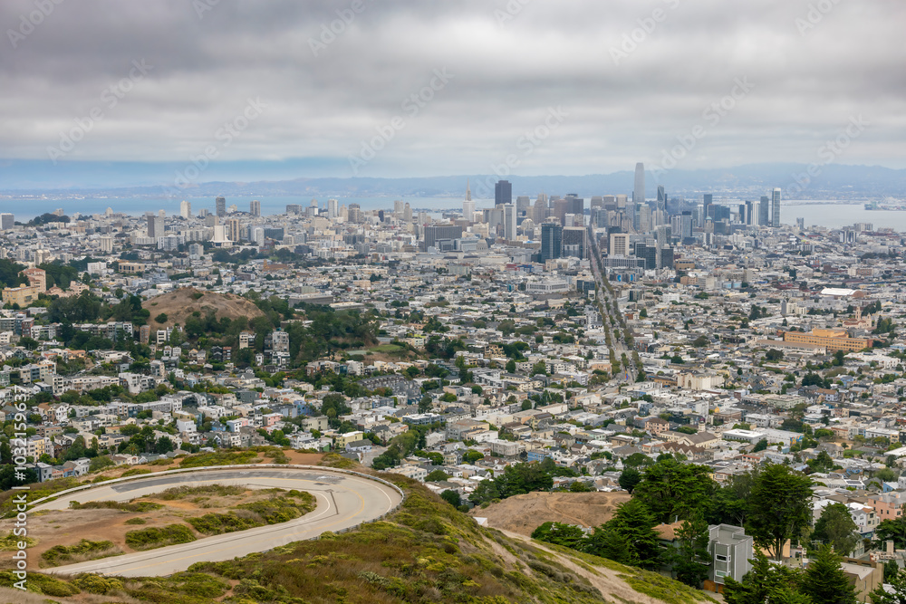 Obraz premium A breathtaking view of San Francisco from Twin Peaks, showcasing its iconic skyline and vibrant cityscape under a blanket of mist and clouds.