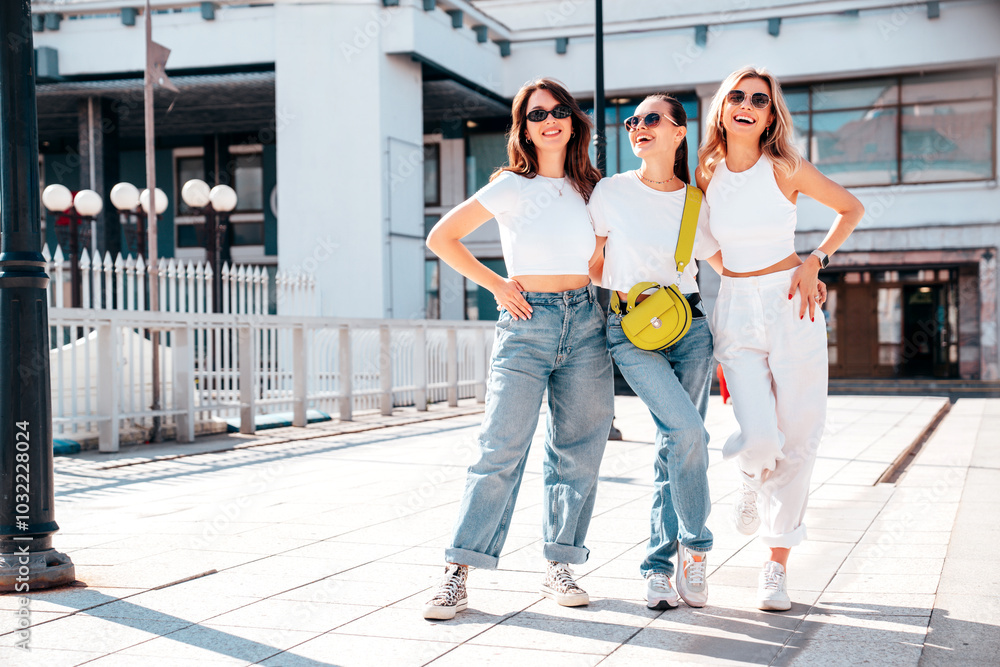 Obraz premium Three young beautiful smiling hipster female in trendy summer white t-shirt and jeans clothes. Sexy carefree women posing in street. Positive models having fun, going crazy. In sunny day, sunglasses