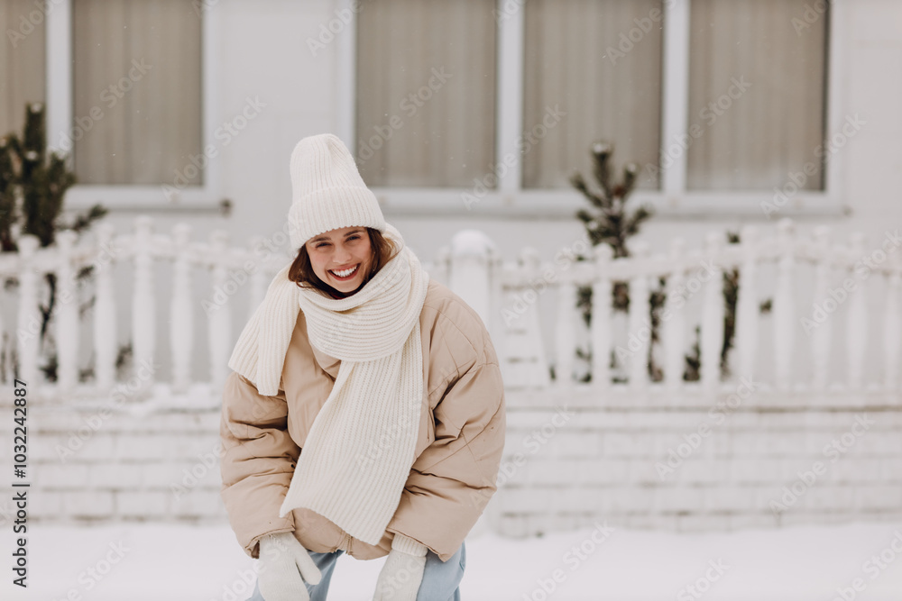 Happy smiling young woman portrait dressed coat scarf hat and mittens enjoys winter weather at snowy house city street Happy smiling young woman portrait dressed coat scarf hat and mittens enjoys winter weather at snowy house city street