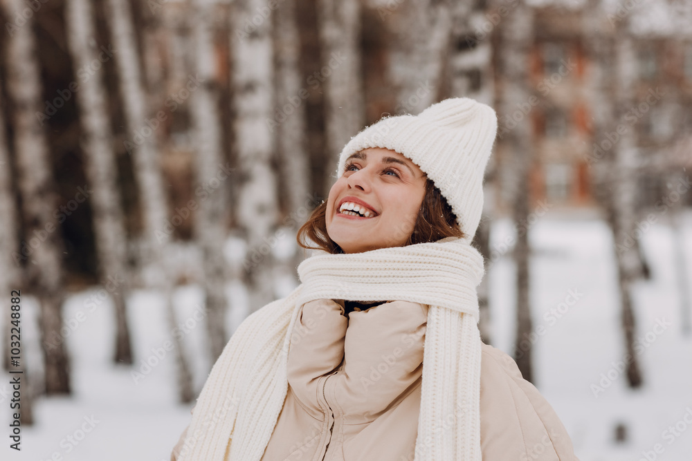 Young smiling woman dressed coat scarf hat and mittens enjoys winter weather at birch winter park