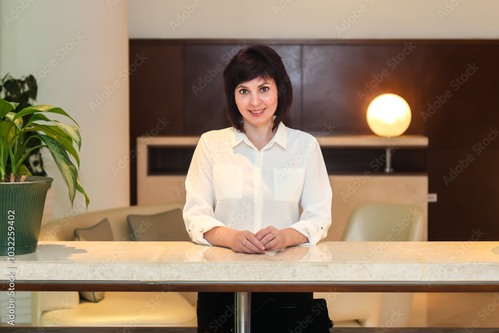A friendly hotel receptionist greets visitors at the counter. A friendly hotel receptionist greets visitors at the counter.