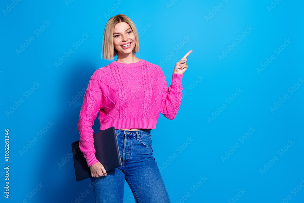 Portrait of nice young woman hold laptop direct finger empty space wear pink sweater isolated on blue color background Portrait of nice young woman hold laptop direct finger empty space wear pink sweater isolated on blue color background