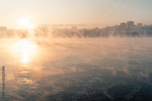 Obraz na płótnie Cold fog over the river at the sunset with city on the background. w salonie