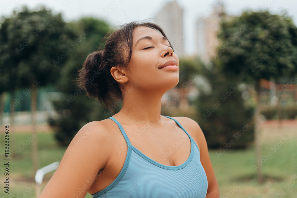 Beautiful young African American woman wearing sportwear with closed eyes breathing on the street Beautiful young African American woman wearing sportwear with closed eyes breathing on the street