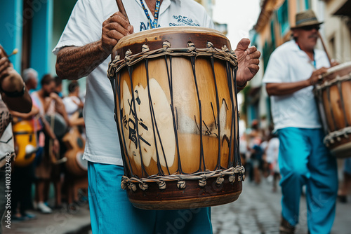 Dos músicos panameños tocan un tambor de cuero en plena calle, con trajes típicos y una multitud alegre celebrando las Fiestas Patrias al ritmo de la música tradicional.
