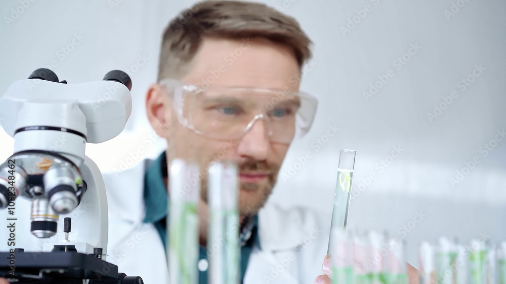 Man with safety glasses is working with lab tubes using a pipette in a modern laboratory, close-up of researcher. Science and medicine Man with safety glasses is working with lab tubes using a pipette in a modern laboratory, close-up of researcher. Science and medicine
