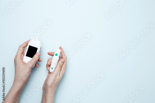 Concept of worldwide diabetes awareness. Woman hands holding glucometer for measuring blood glucose levels,  lancet photo