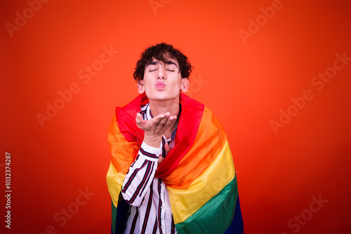 Funny young man posing in studio with gay flag.