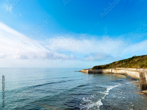 A 390 metre seawall construction built to protect further erosion and stabilise the cliffs along the  coastline east of Lyme Regis in Dorset captured on a sunny day with soft fluffy clouds photo