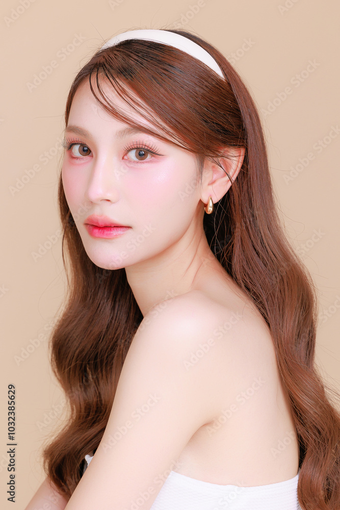 Pretty Asian beauty woman curly long hair with Korean makeup glowing face and healthy facial skin portrait smile on isolated beige background. Cosmetology ,Plastic surgery. Pretty Asian beauty woman curly long hair with Korean makeup glowing face and healthy facial skin portrait smile on isolated beige background. Cosmetology ,Plastic surgery.