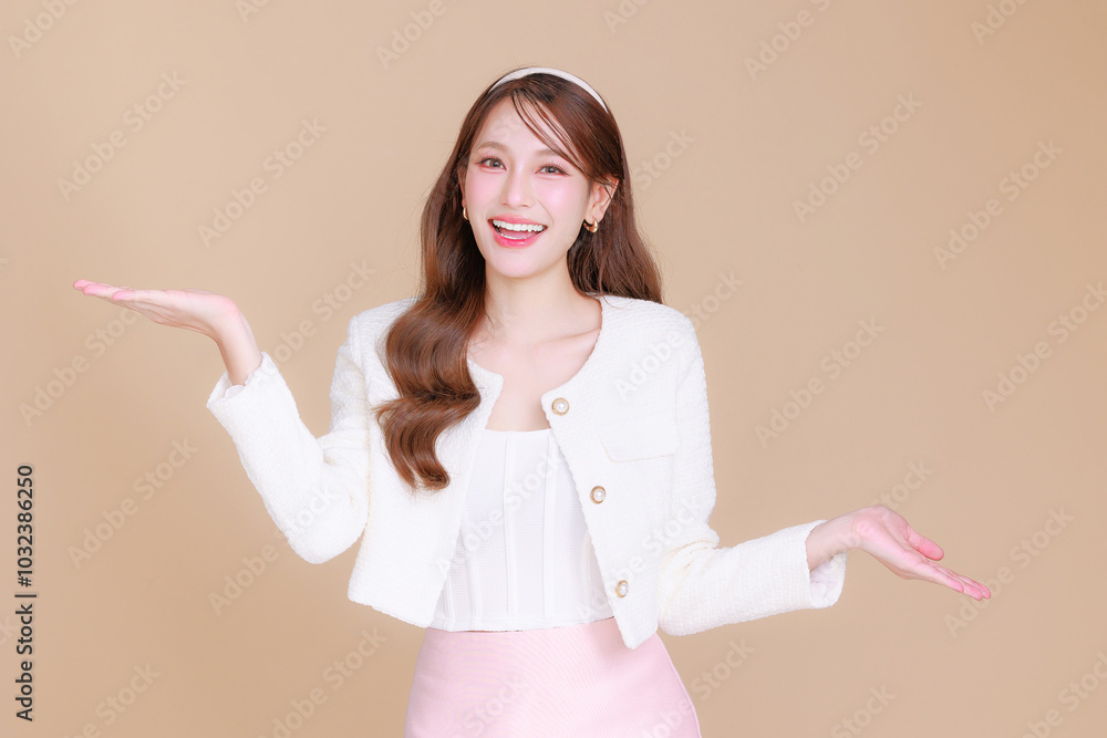 Pretty smiling young office Asian business entrepreneur smile showing open hand palm standing on isolated beige background. Pretty smiling young office Asian business entrepreneur smile showing open hand palm standing on isolated beige background.