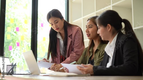 Women in modern office engage in collaboration and discussion, showcasing teamwork and professionalism while reviewing important documents and ideas during productive meeting.