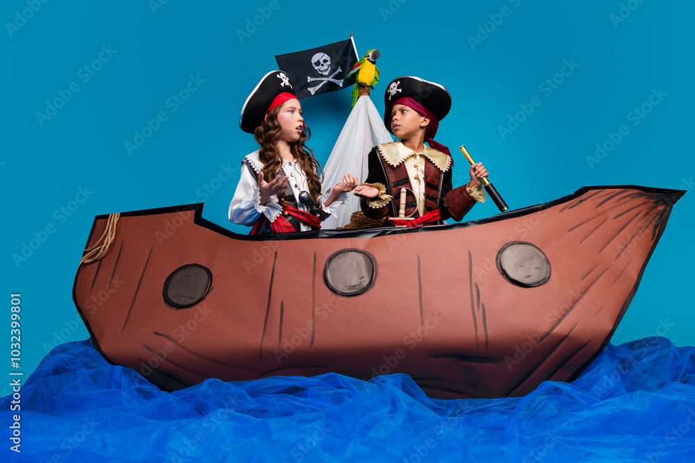 Full size photo of two little children confused shrug shoulders wear pirates halloween costumes ship decor isolated on blue background Full size photo of two little children confused shrug shoulders wear pirates halloween costumes ship decor isolated on blue background
