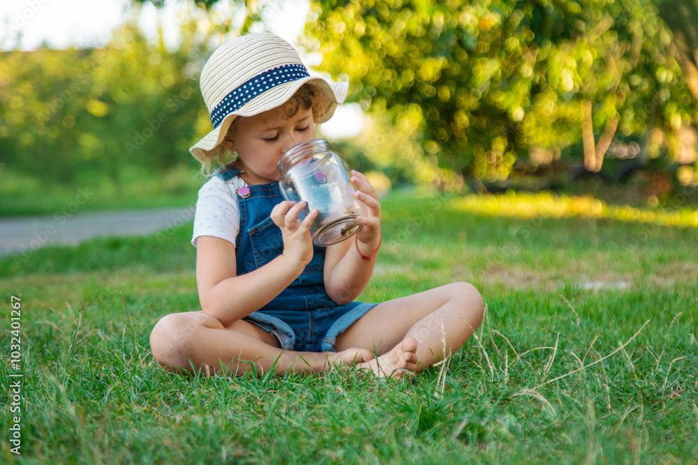 A child looks through a magnifying glass in nature. Selective focus. A child looks through a magnifying glass in nature. Selective focus.