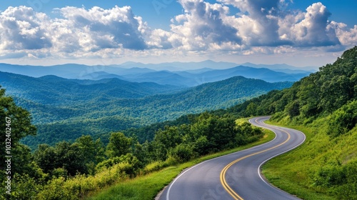 A winding road through lush mountains under a blue sky with fluffy clouds.