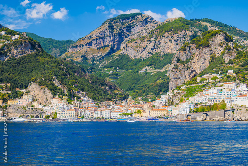 Amalfi, Italy. View of Amalfi and Amalfi Coast from the sea. Seaside village with green mountains of Monti Lattari in Campania, Italy. Seascape on a sunny summer day.