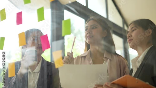 Women in modern office engage in teamwork and collaboration, using colorful sticky notes for brainstorming and planning, showcasing their creativity and focused expressions.