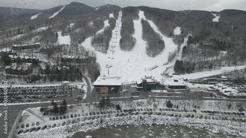 the snow covering the Loon Mountain Resort with a filled parking lot in Lincoln, New Hampshire photo