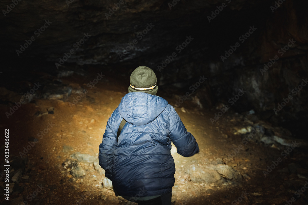 A person is cautiously walking through a dark cave while holding a flashlight to illuminate the way ahead, ensuring safety amidst the shadows and uncertainty of their surroundings A person is cautiously walking through a dark cave while holding a flashlight to illuminate the way ahead, ensuring safety amidst the shadows and uncertainty of their surroundings