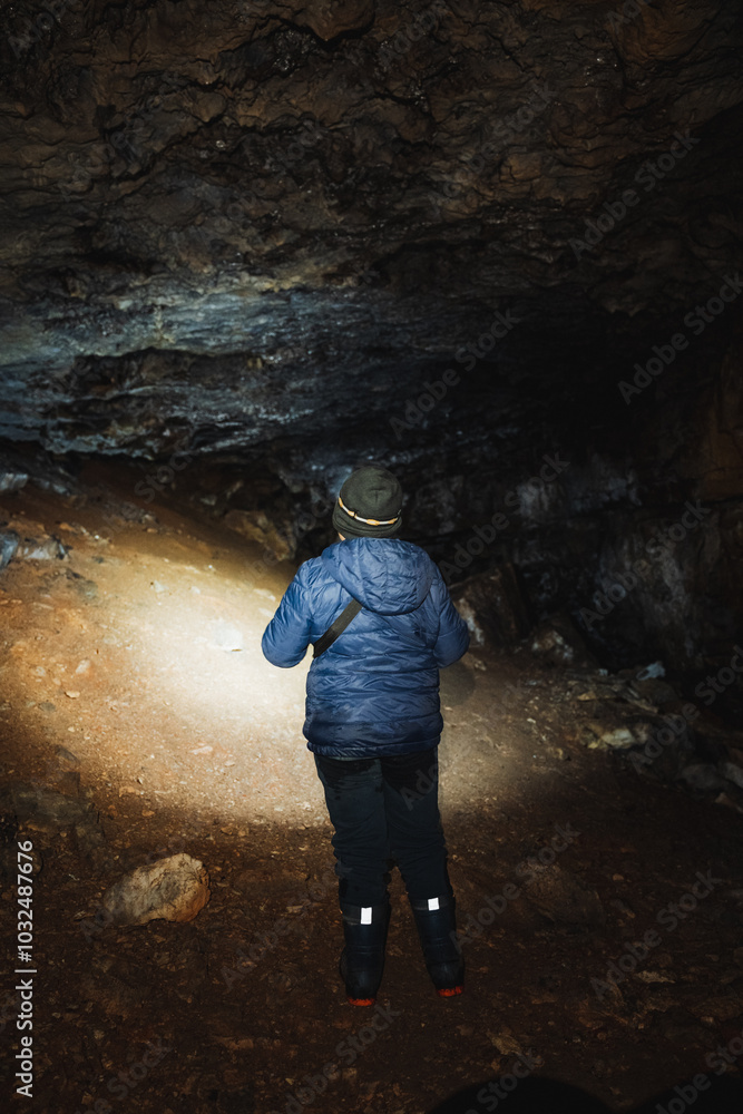 A solitary individual stands in a mysterious cave, illuminating their surroundings with a bright flashlight, creating a stunning contrast against the oppressive darkness on their adventurous journey A solitary individual stands in a mysterious cave, illuminating their surroundings with a bright flashlight, creating a stunning contrast against the oppressive darkness on their adventurous journey