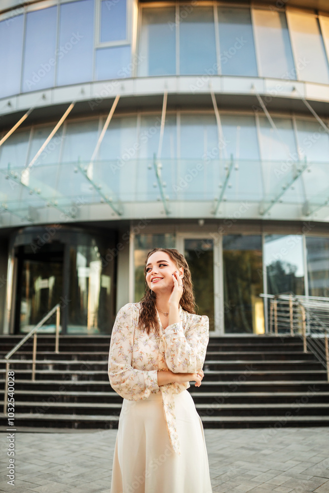 Smiling young woman dreams and is on the street near a business cente Smiling young woman dreams and is on the street near a business cente