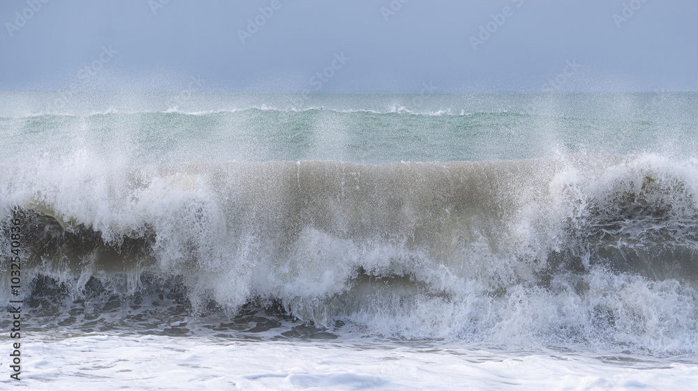 Obraz premium The ocean is rough and the waves are crashing against the shore. The sky is cloudy and the water is a deep blue color