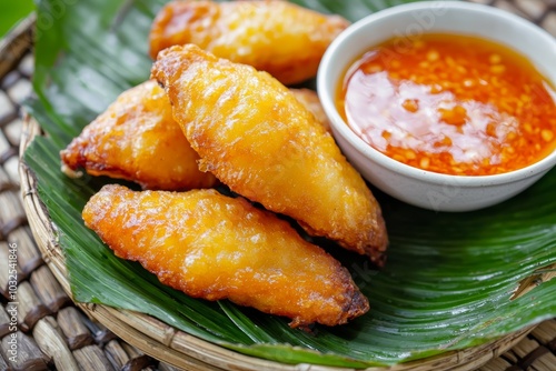 Golden, crispy deep-fried tofu stacked high on a street vendor s tray, with spicy chili sauce dipping bowls in the foreground photo