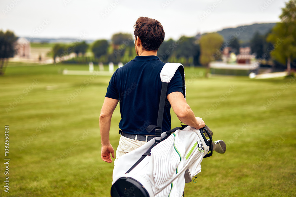 Obraz premium A Golfer is Walking on the Golf Course with His Clubs as He Enjoys the Beautiful Day