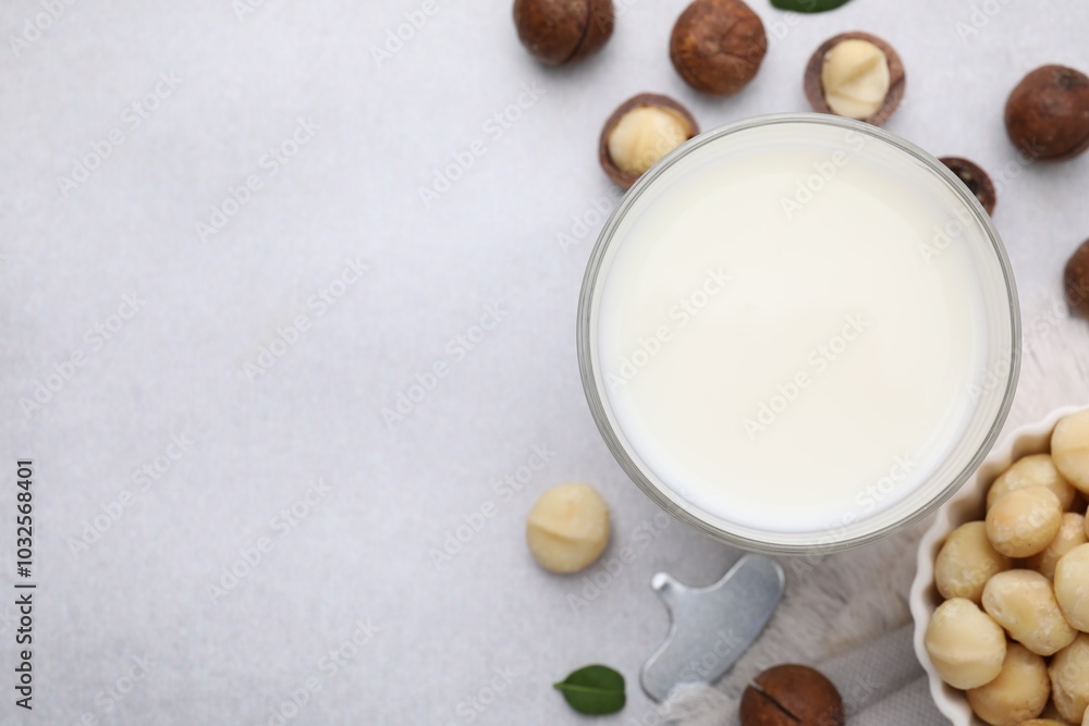 Glass of macadamia milk and nuts on white table, flat lay. Space for text Glass of macadamia milk and nuts on white table, flat lay. Space for text