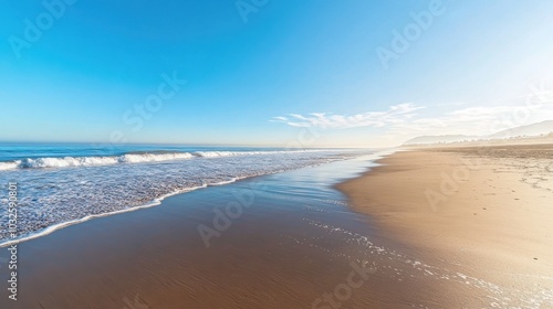 A tranquil empty beach on a sunny day with calm waves and clear blue skies overlooking the serene shoreline