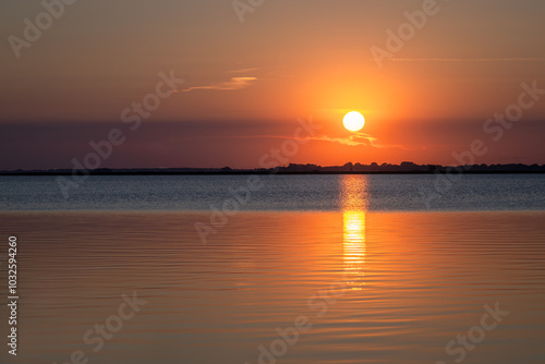 Sonnenuntergang über ruhigem See mit reflektierendem Licht auf der Wasseroberfläche photo