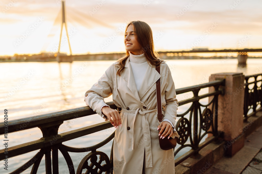 A young woman walks along the embankment and enjoys the warm autumn sunset. Lifestyle, travel, tourism, active life. A young woman walks along the embankment and enjoys the warm autumn sunset. Lifestyle, travel, tourism, active life.