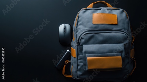 A gray backpack with orange accents and a computer mouse on a dark surface.