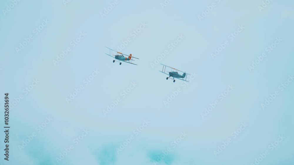 Two old biplane planes fly high in the sky together Two old biplane planes fly high in the sky together