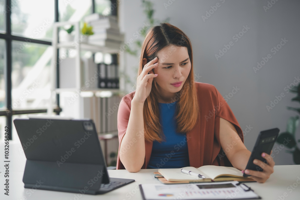Young asian businesswoman is feeling stressed and having a headache while working at her desk in the office Young asian businesswoman is feeling stressed and having a headache while working at her desk in the office