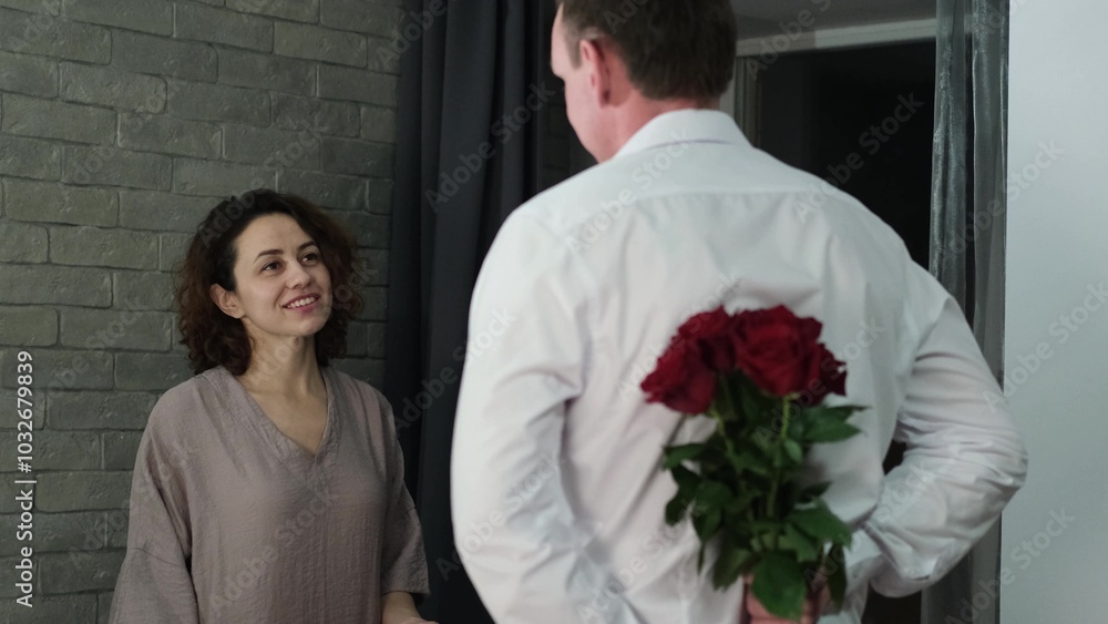 Happy Valentine's Day. A man gives his beloved woman a bouquet of red roses. Husband gives pleasant surprises to his wife Happy Valentine's Day. A man gives his beloved woman a bouquet of red roses. Husband gives pleasant surprises to his wife