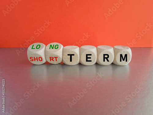 Turned the cubes and changes the expression SHORT TERM to LONG TERM or vice versa. Beautiful grey table, red background. Business concept.