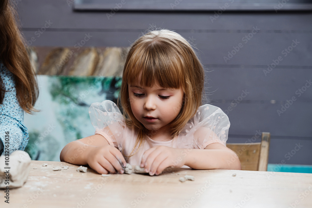 Fototapeta premium child engaged in creative play with clay at a table indoors