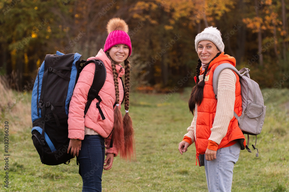 family walking in autumn forest with backpacks, girl in pink jacket, mother in orange sleeveless jacket, family in hat with pompoms, gen z family walking in autumn forest with backpacks, girl in pink jacket, mother in orange sleeveless jacket, family in hat with pompoms, gen z