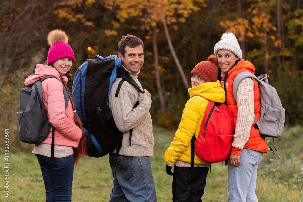 family walking in autumn forest with backpacks, boy in yellow jacket, girl in pink jacket, mother in orange sleeveless jacket, family in hat with pompoms, gen z, father with a big backpack family walking in autumn forest with backpacks, boy in yellow jacket, girl in pink jacket, mother in orange sleeveless jacket, family in hat with pompoms, gen z, father with a big backpack