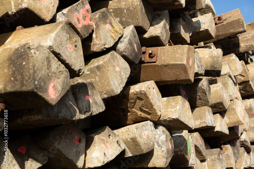 Nahaufnahme eines Stapels von aussortierten Bahnschwellen aus Holz, an denen Schrauben und Winkel montiert sind. photo