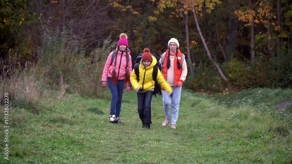 family walking in autumn forest with backpacks, boy in yellow jacket, girl in pink jacket, mother in orange sleeveless jacket, family in hat with pompoms, gen z family walking in autumn forest with backpacks, boy in yellow jacket, girl in pink jacket, mother in orange sleeveless jacket, family in hat with pompoms, gen z