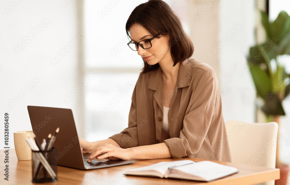 Pensive Worker. Portrait of smiling girl in eyeglasses using laptop, sitting at office and doing research, copyspace Pensive Worker. Portrait of smiling girl in eyeglasses using laptop, sitting at office and doing research, copyspace